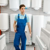 Installateur mit einem Heizkörper unter dem Arm