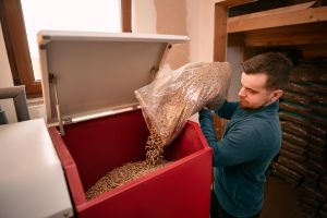 Mann füllt Holzpellets in eine Pelletheizung